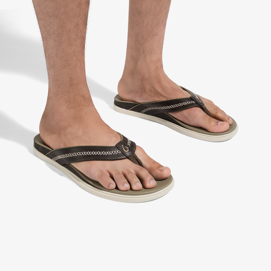 Black and cream thong flip-flops with woven strap detail, worn on feet.