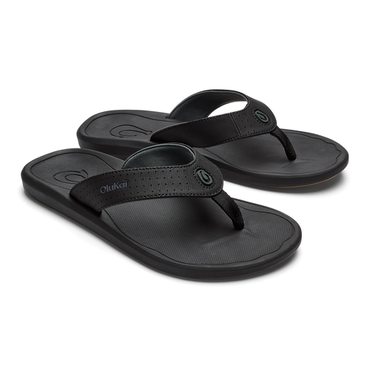 Two black OluKai flip-flops with textured footbeds and woven straps displayed side by side.