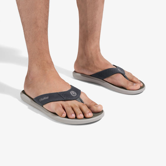 Men's flip-flop sandals with dark gray straps and light gray soles, worn on bare feet.
