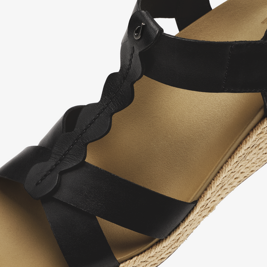 Black and warm sand suede sandal with scalloped ankle strap and woven jute sole.