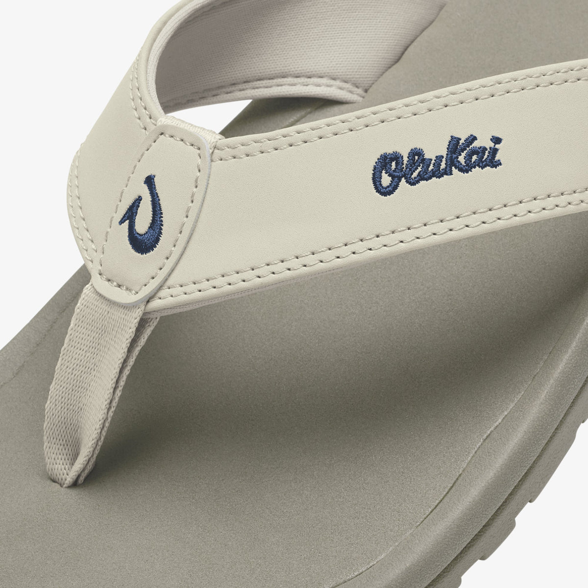 Cream-colored thong sandal with navy embroidered "Ohana" text and curved logo detail on the upper strap.