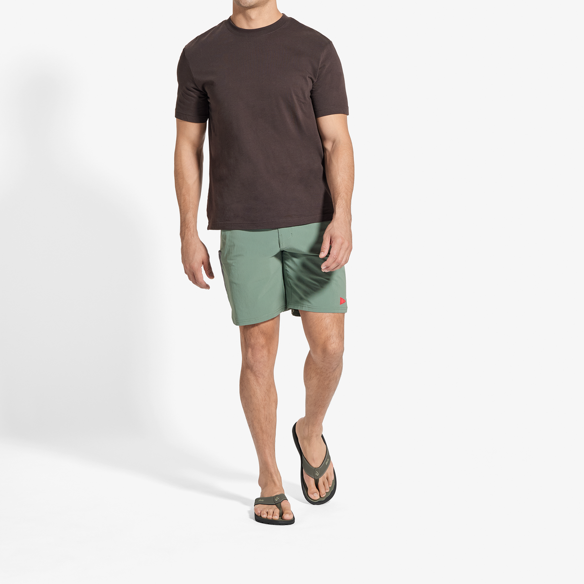 Man wearing dark brown t-shirt and sage green shorts with red accent detail.