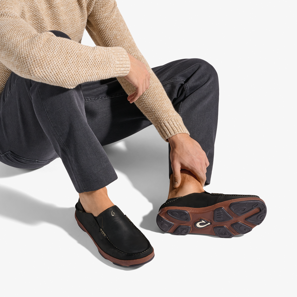 Black slip-on shoe with toffee-brown sole, worn with cream knit sweater and dark jeans.