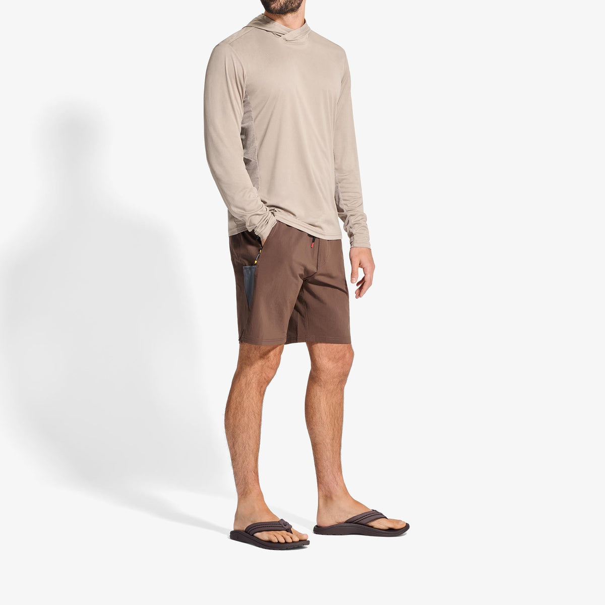 Man wearing beige long-sleeve shirt, dark brown shorts, and black slide sandals.