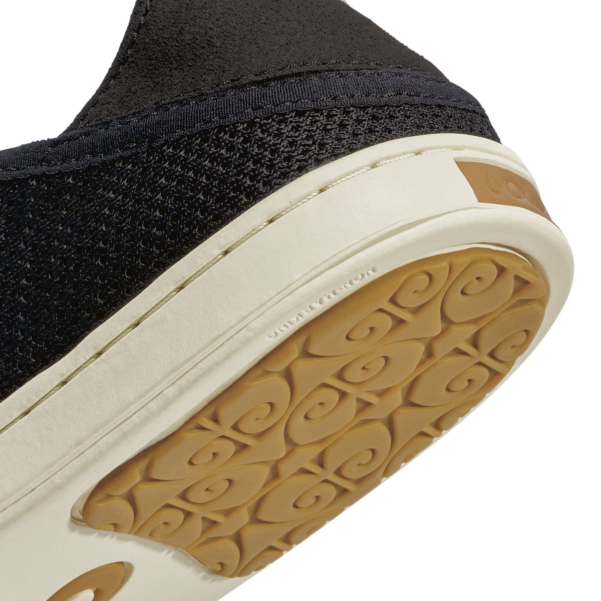 Black knit slip-on shoe with cream midsole, tan leather heel patch, and tan patterned outsole.