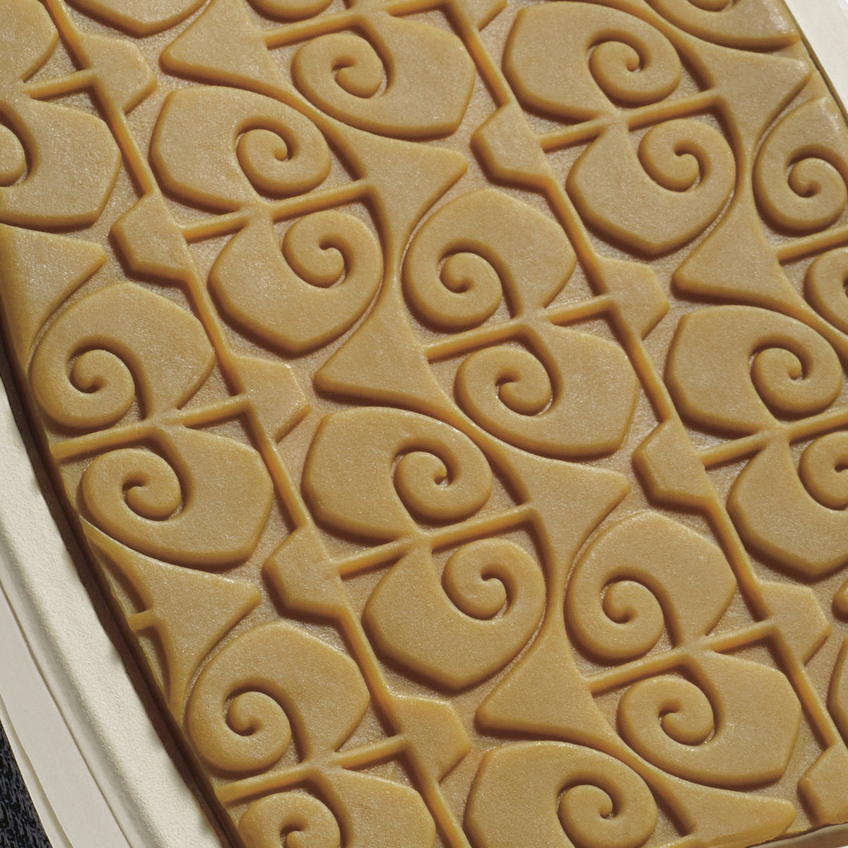 Tan shoe sole with embossed spiral and curved geometric pattern detail.