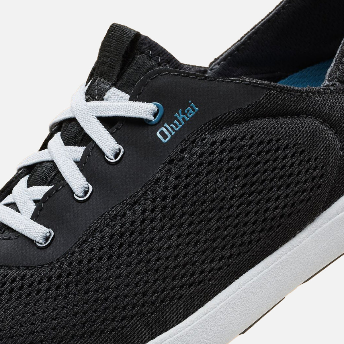 Black lace-up sneaker with white shoelaces, blue coral accents, and textured knit upper panel.