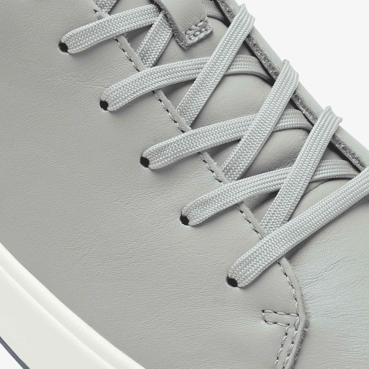 Grey leather sneaker with white laces and white sole detail.
