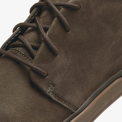 Dark brown suede boot with lace-up closure and tan sole visible.