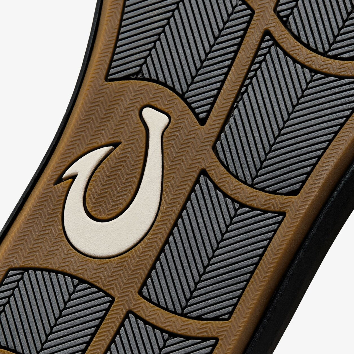 Tan and black patterned surface featuring white fish hook symbol and leaf-like designs.