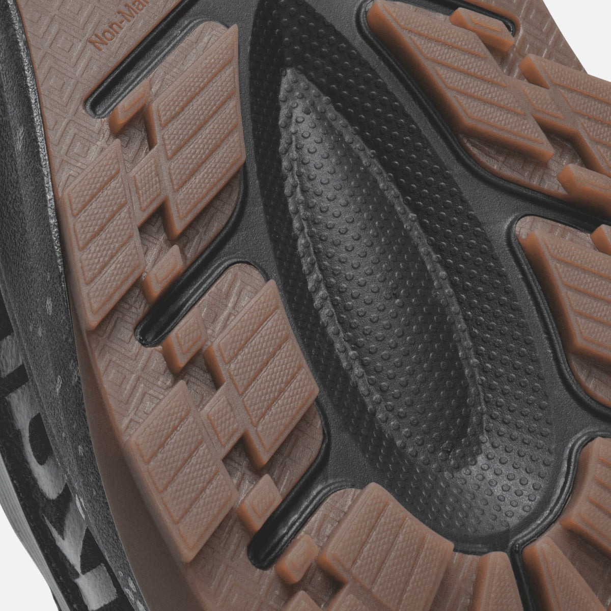 Black shoe sole with brown textured tread pattern and grip dots visible from underside view.