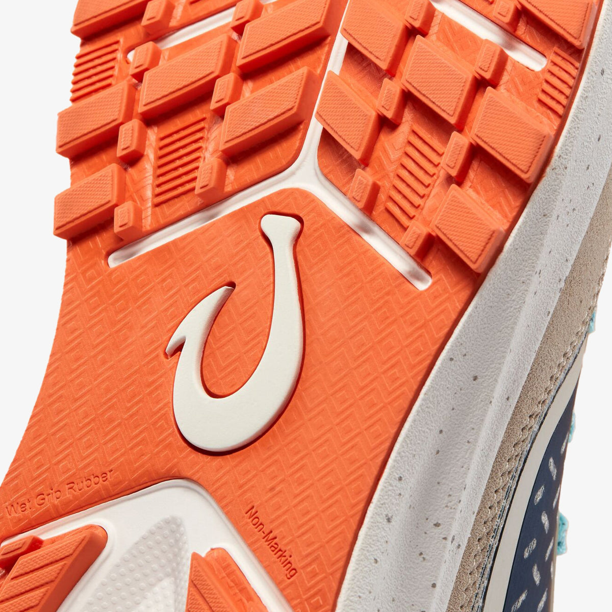 Orange and white rubber shoe sole with textured tread pattern and hook logo detail.