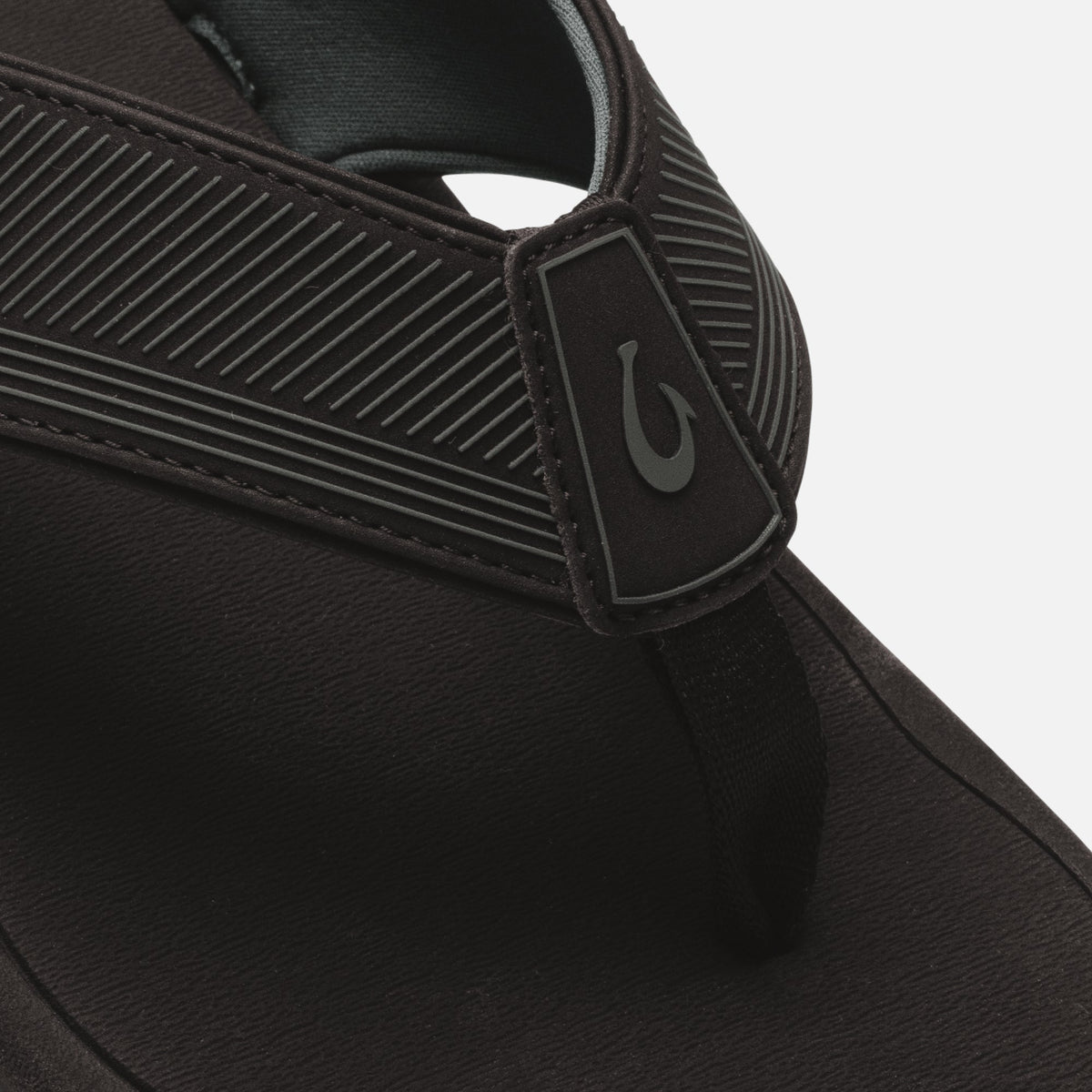 Black slide sandal with textured ribbed straps and logo patch detail on the upper.