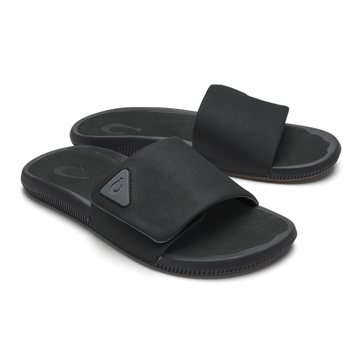 Pair of black slide sandals with textured straps and cushioned soles.