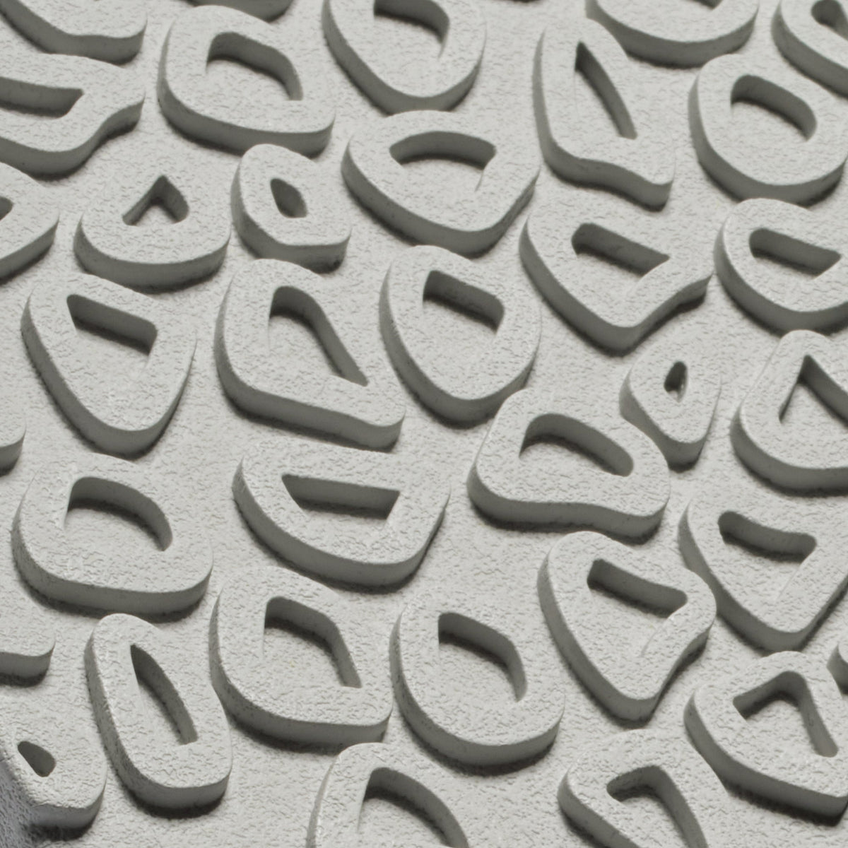 Close-up of light grey textured shoe sole with curved tread pattern and oval cutout designs.