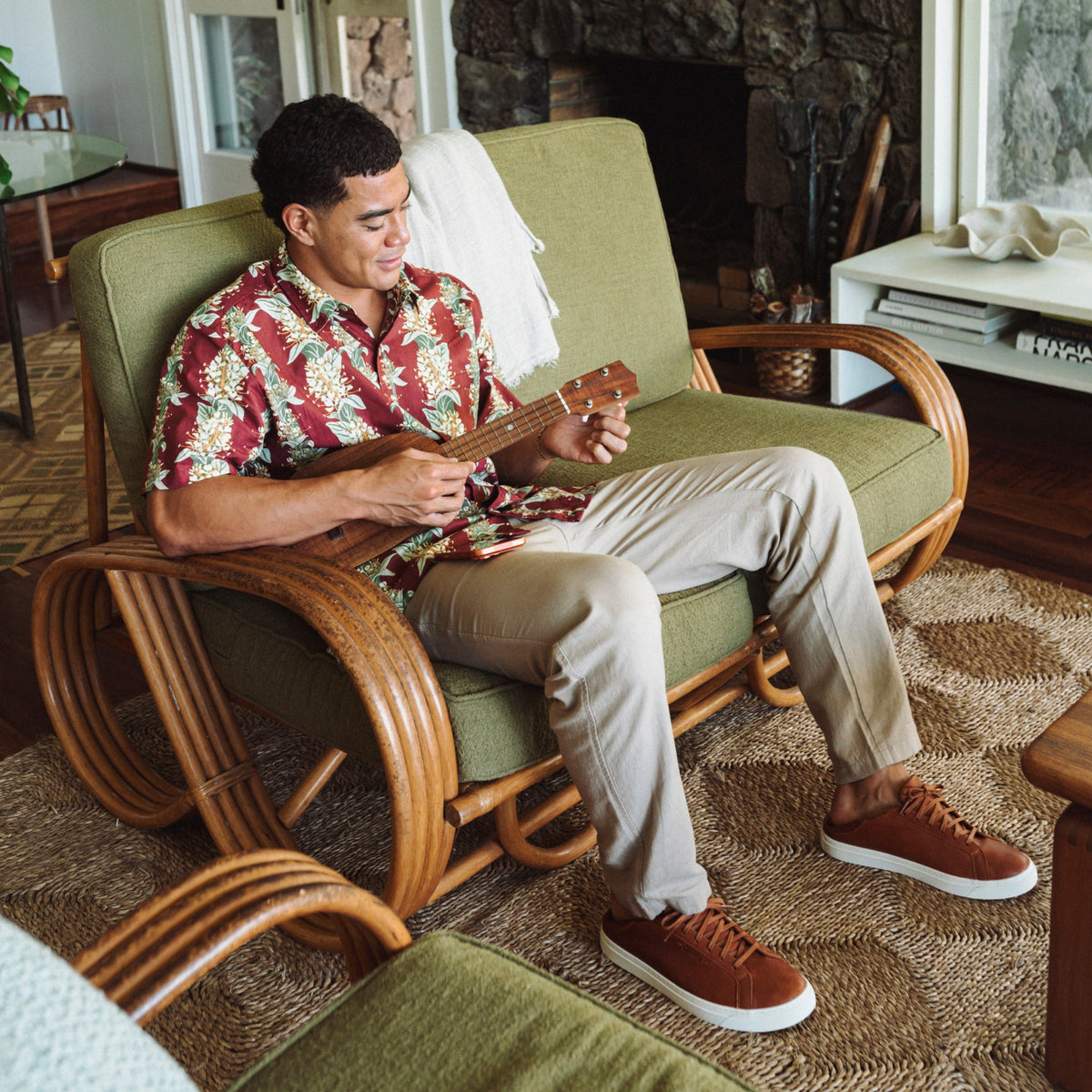 Brown lace-up sneaker with white sole worn by person sitting on chair.