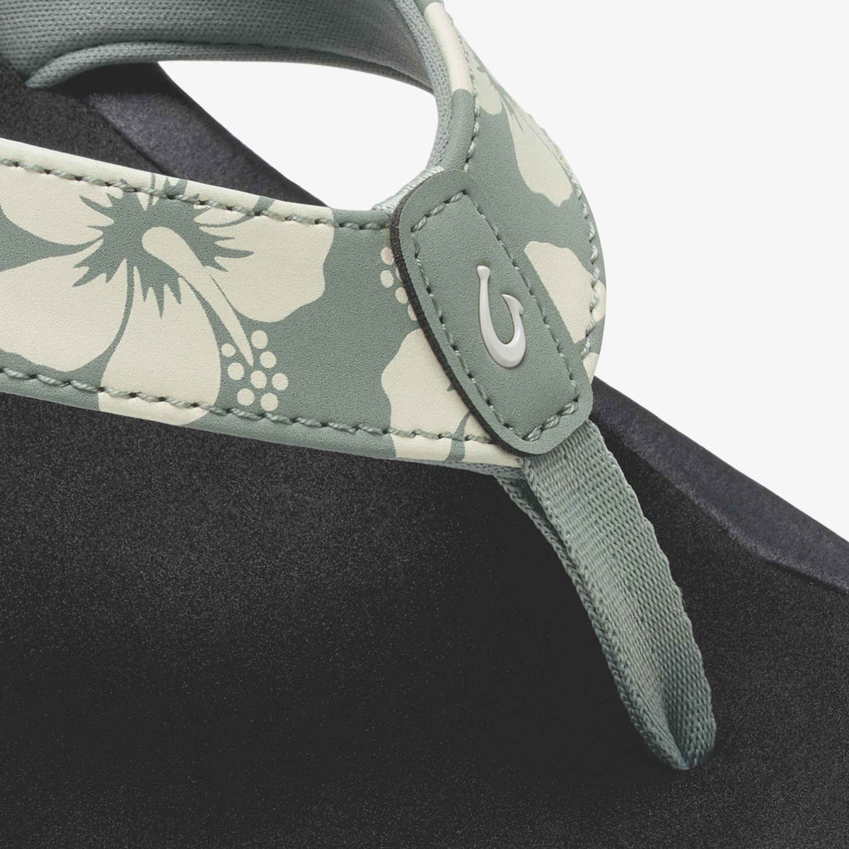 Teal and cream floral patterned strap with hook closure on black fabric material.