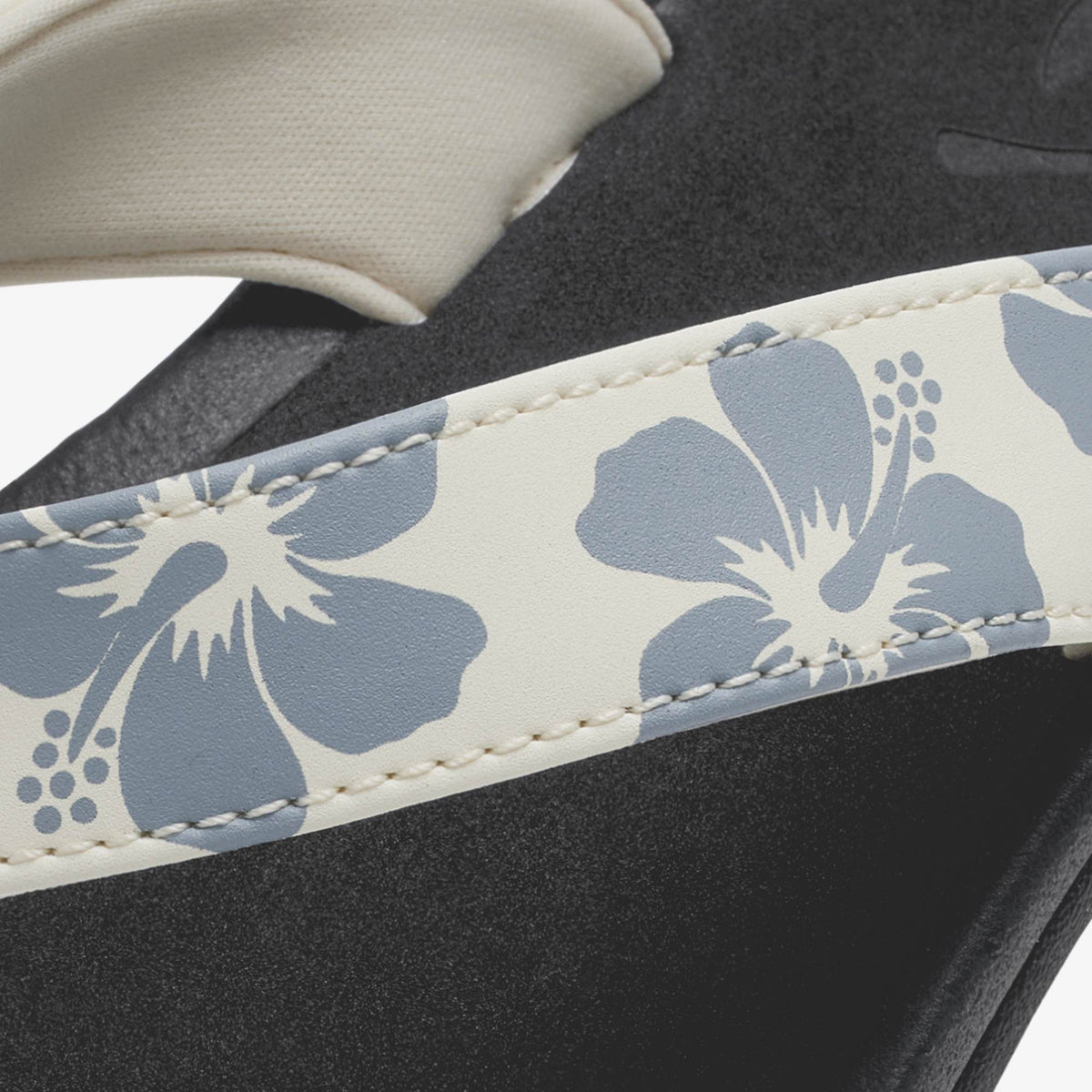 White and blue floral patterned strap on black footwear with cream-colored sole detail.