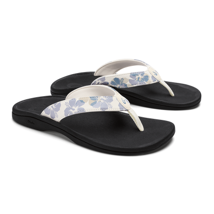 Pair of black flip-flops with white straps featuring blue floral pattern.