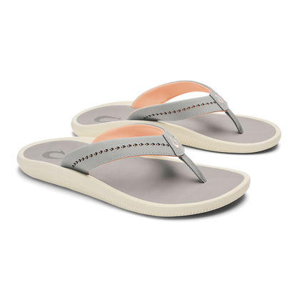 Pair of gray and cream flip-flop sandals with studded straps and peach-colored heel accents.