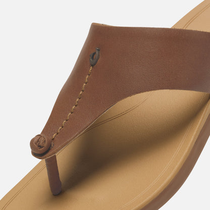 Toffee-brown leather thong sandal with warm sand-colored sole and decorative stitched strap detail.