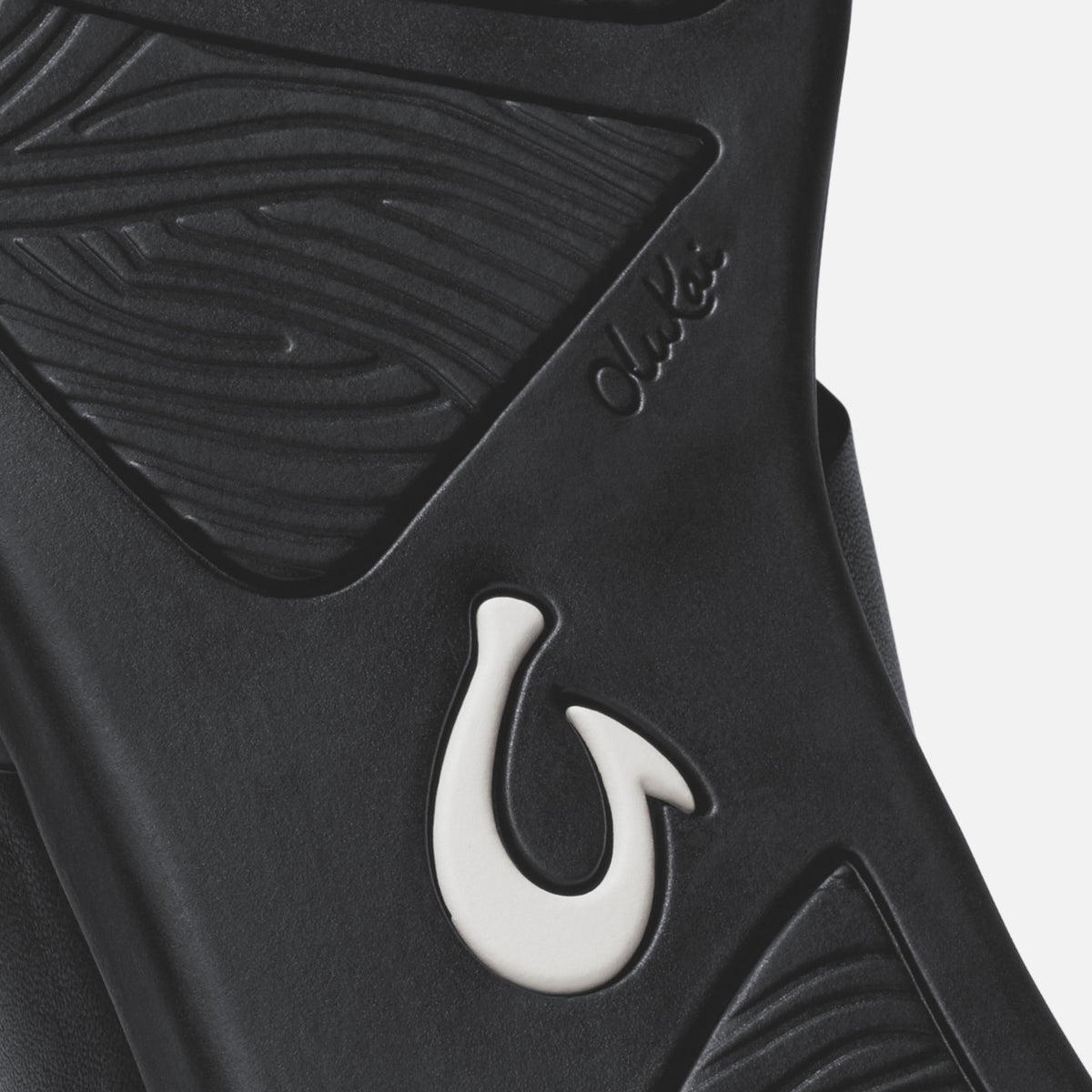 Black sandal with white hook detail and textured upper strap design.