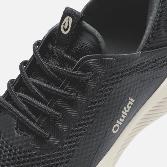 Black Kialoa sneaker with textured lava rock pattern, white sole, and cream-colored heel tab detail.