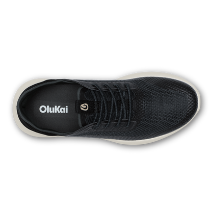 Black mesh OluKai sneaker with lace-up closure and cream-colored sole, viewed from above.