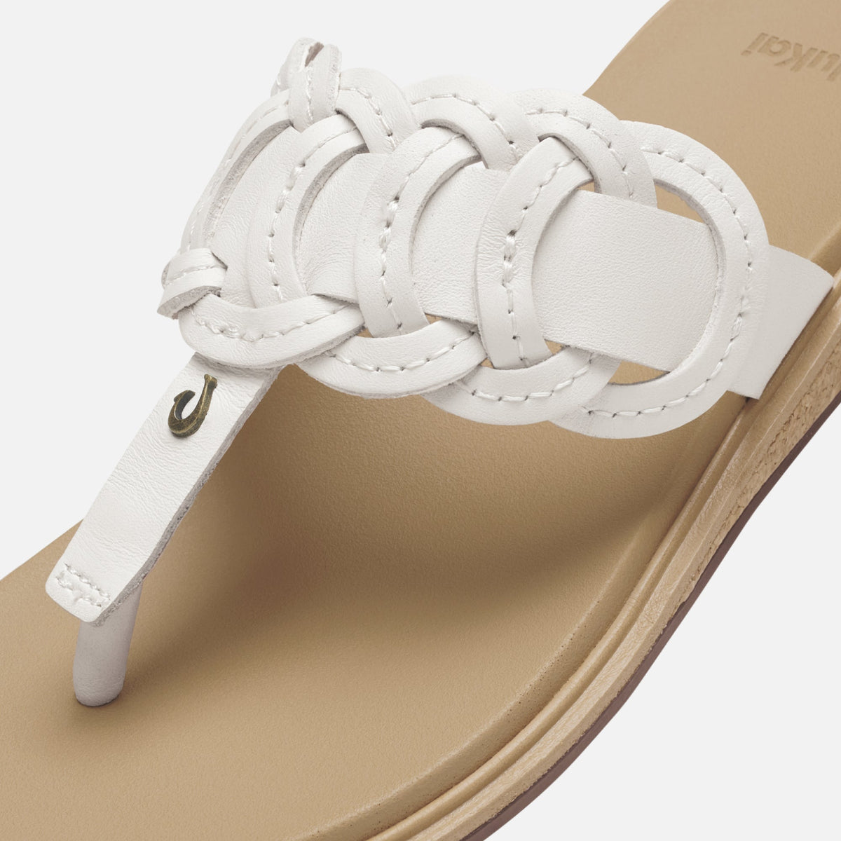 White leather sandal with braided strap detail and warm sand-colored footbed, shown from above.