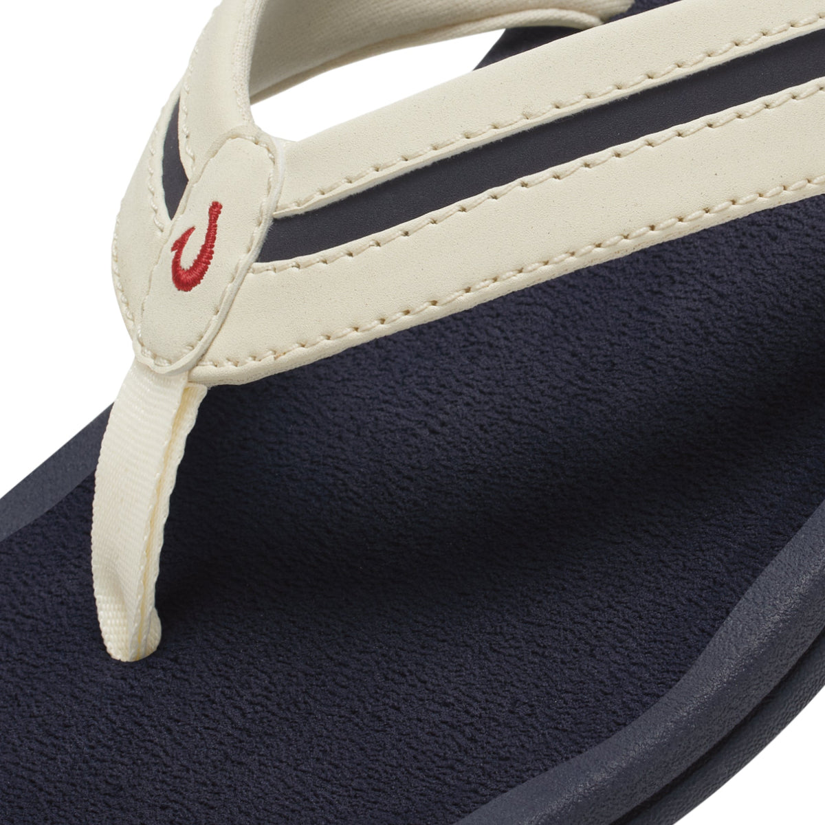 White sand and navy thong sandal with red logo detail on toe post.