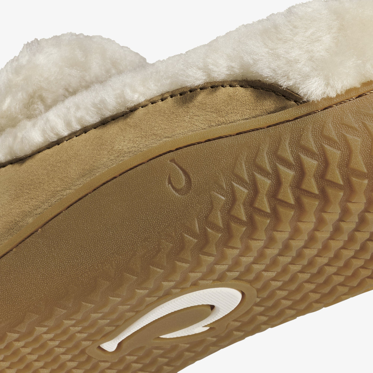 Tan leather slipper with cream fleece lining and textured sole with white accent logo.