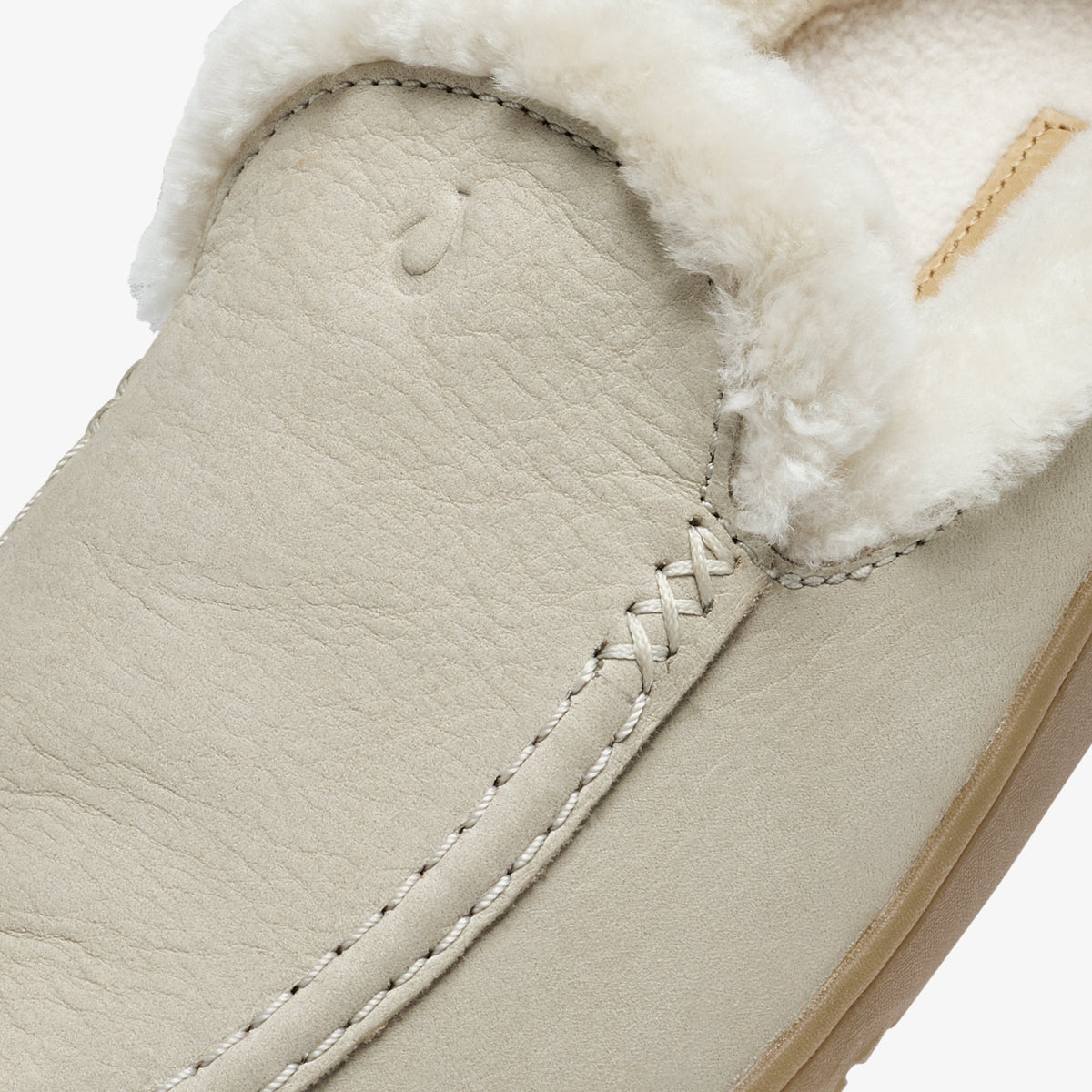 Ecru leather slip-on shoe with white fleece collar trim and cross-stitch detailing on the vamp.