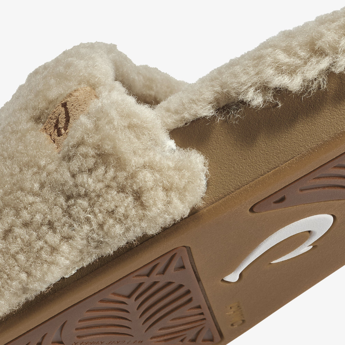 Tan leather sandal with cream fleece lining and textured sole detail, shown in close-up view.
