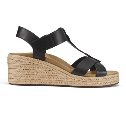 Black leather T-strap sandal with woven jute wedge heel and warm sand-colored suede footbed.