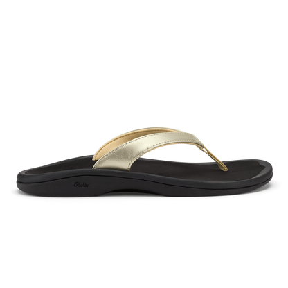 Gold metallic thong strap sandal with black cushioned sole and curved footbed.