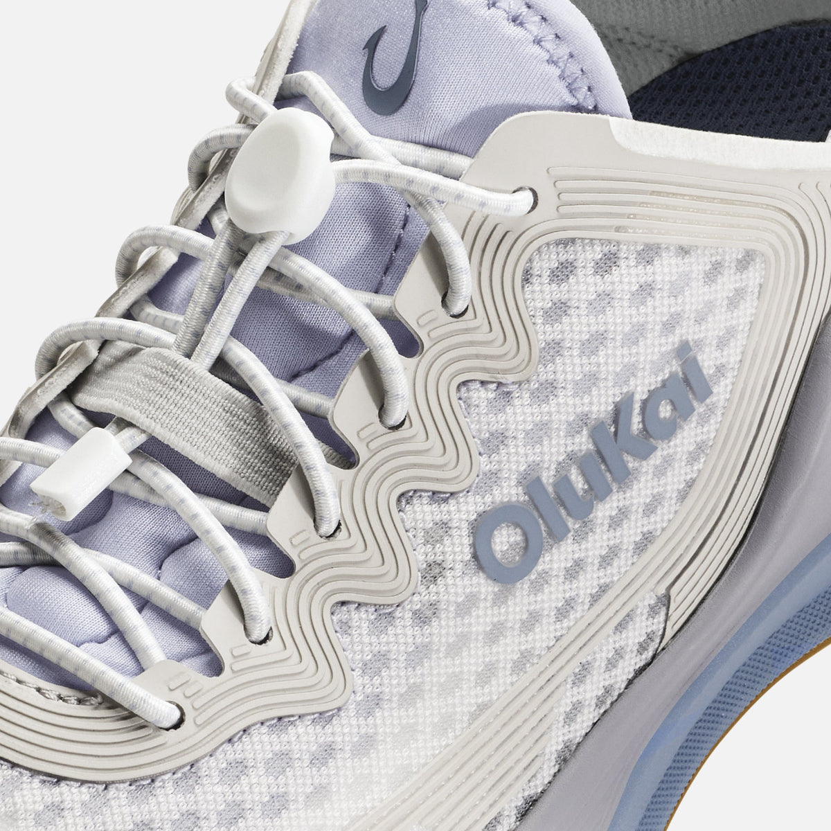 White and lavender sneaker with white laces, "Oma" branding, and textured side panel detail.