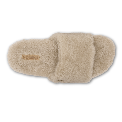 Tan fleece slipper with textured cushioned sole and OluKai branding on insole, shown from top view.