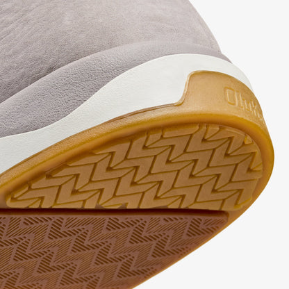 Closeup of shoe sole showing gray textile upper, white midsole, and tan rubber outsole with geometric tread pattern.